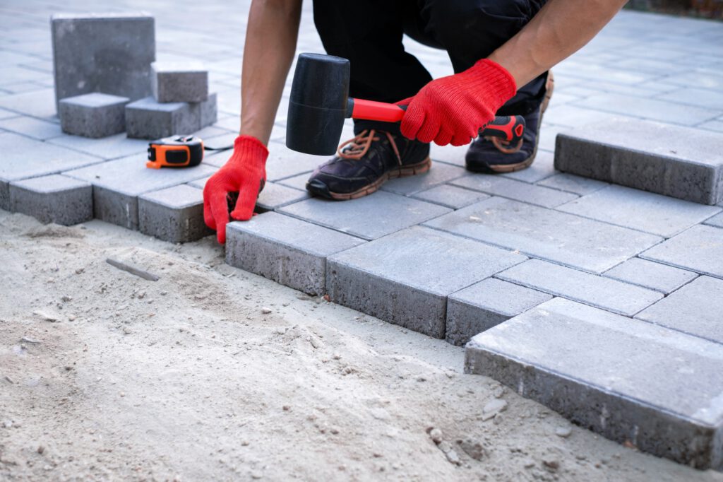 The master in yellow gloves lays paving stones