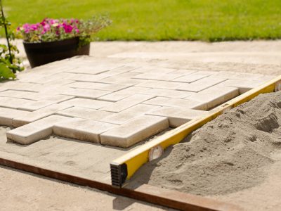 The master lays paving stones in layers. Garden brick pathway paving by professional paver worker.